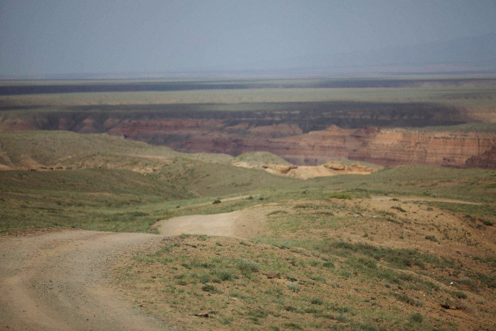 An unpaved road running straight across open desert toward distant hills