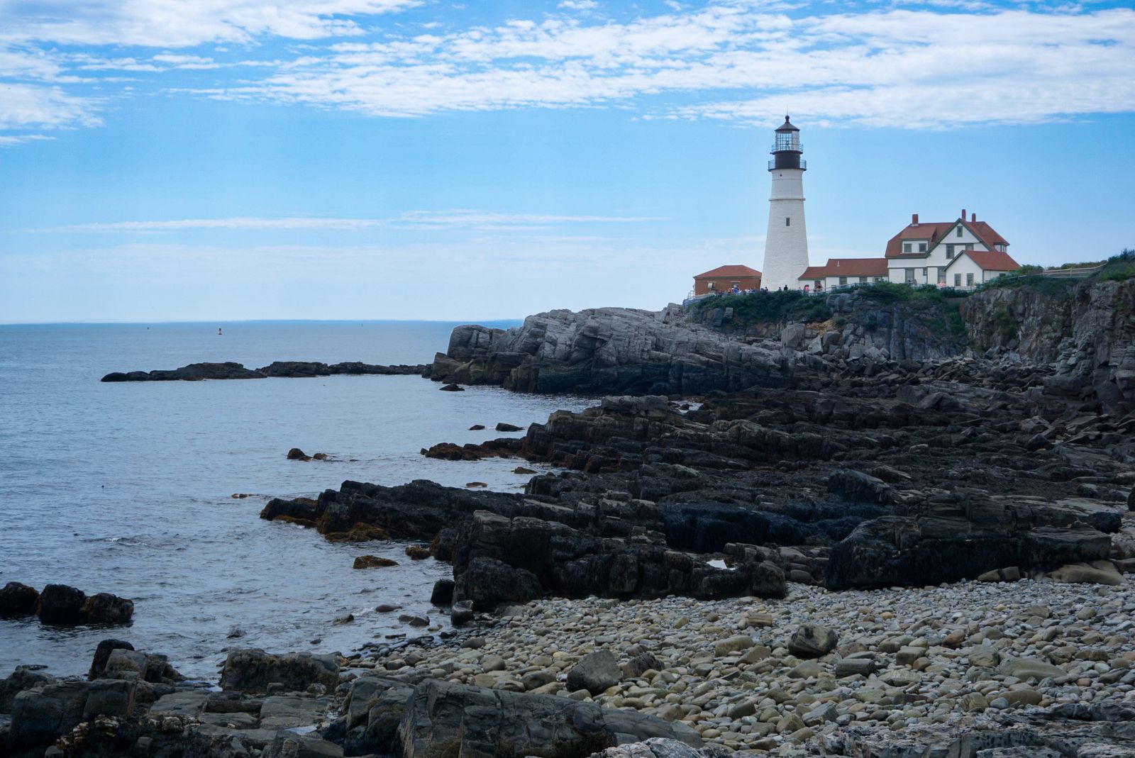 A lighthouse standing on a rocky headland above breaking sea